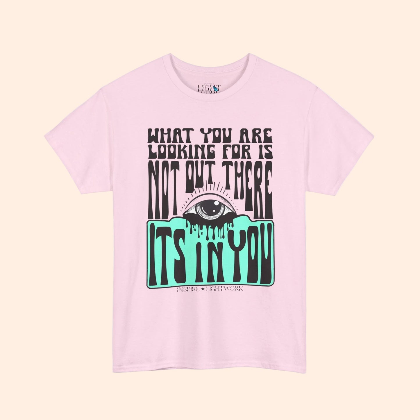 Pink t-shirt with eye graphic and motivational text on a white background that says "what youre looking for isnt out there its in you"