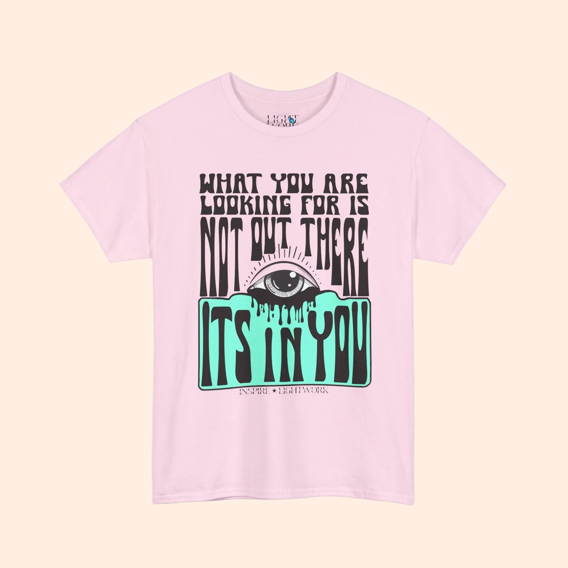 Pink t-shirt with eye graphic and motivational text on a white background that says "what youre looking for isnt out there its in you"