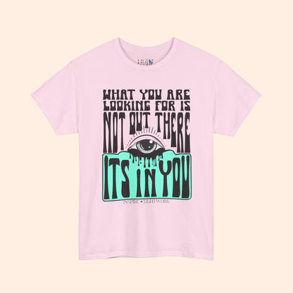 Pink t-shirt with eye graphic and motivational text on a white background that says "what youre looking for isnt out there its in you"
